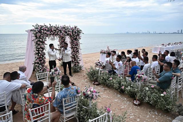 Chinese nationals Song Jihan (centre L) and Wang Zengyi (centre R) sing together during their wedding ceremony near Pattaya in Chonburi province on May 31, 2025. When Wang Zengyi, 41, and Song Jihan, 29, first met at a friend's dinner party in China, it was love at first sight. Nearly three years later, the gay Chinese couple are getting married in Thailand, which became Asia's largest nation to legalise same-sex marriage earlier this year - including for foreign couples. (Photo by Lillian SUWANRUMPHA / AFP) / To go with Thailand-China-rights-LGBTQ, REPORTAGE by Sarah LAI (STF), Sally JENSEN