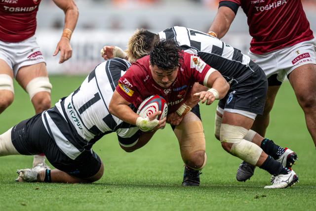 Toshiba Brave Lupus Tokyo's Sena Kimura (C) is tackled by Kubota Spears Funabashi Tokyo Bay's Yota Kamimori (L) during the Rugby League One 2024-25 play-offs final between Toshiba Brave Lupus Tokyo and Kubota Spears Funabashi Tokyo Bay at the National Stadium in Tokyo on June 1, 2025. (Photo by Philip FONG / AFP)