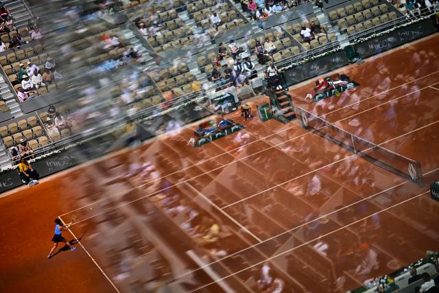 Spectators are reflected in a glass as Italy's Jasmine Paolini (L) plays against Ukraine's Elina Svitolina during their women's singles match on day 8 of the French Open tennis tournament on Court Philippe-Chatrier at the Roland-Garros Complex in Paris on June 1, 2025. (Photo by JULIEN DE ROSA / AFP)