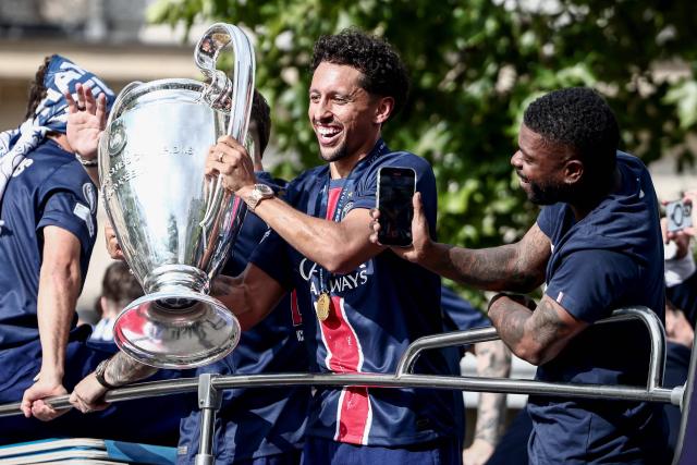 Paris Saint-Germain's Brazilian defender #05 Marquinhos (C) holds the UEFA Champions League Trophy during a parade on the Champs-Elysees avenue in Paris on June 1, 2025, a day after PSG won the 2025 UEFA Champions League final football match against Inter Milan in Munich. (Photo by Thibaud MORITZ / AFP)