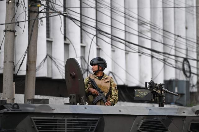 An Army soldier secures the area from an armored vehicle before El Salvador's President Nayib Bukele delivers his first-year speech outside the National Theatre in San Salvador on June 1, 2025. (Photo by Marvin RECINOS / AFP)