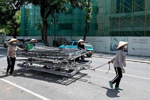 Women pull a trailer loaded with scrap metal in Hanoi on June 2, 2025. (Photo by Nhac NGUYEN / AFP)