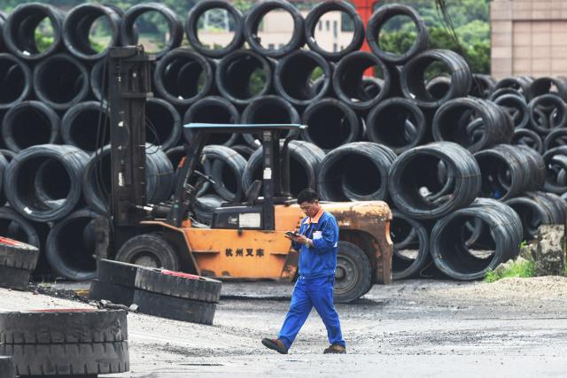 A worker walks past rolls of steel at a steel market in Hangzhou, in eastern China's Zhejiang province on June 4, 2025. (Photo by AFP) / China OUT