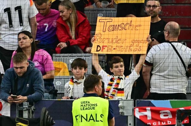 A yuoung germany fan holds up a placard which reads "Swap my brother for a jersey of the German team" prior to the UEFA Nations League semi-final football match between Germany and Portugal in Munich, southern Germany on June 4, 2025. (Photo by Tobias SCHWARZ / AFP)