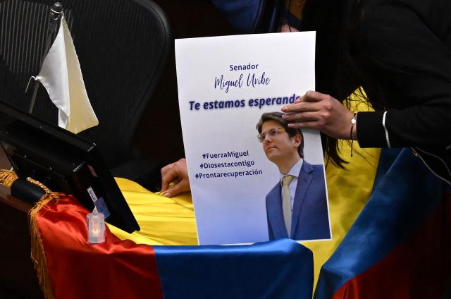 Lawmakers place a photo of Colombian senator and presidential candidate Miguel Uribe with the phrase "We are waiting for you" on a Colombian flag above his seat at the Congress in Bogota on June 9, 2025. Doctors treating a Colombian presidential hopeful shot twice in the head by a would-be assassin warned he was not responding well to treatment Monday and that his condition remained grave. Right-wing Senator Miguel Uribe, 39, was shot by a 15-year-old alleged hitman at close range while campaigning in Bogota on Saturday. (Photo by Raul ARBOLEDA / AFP)