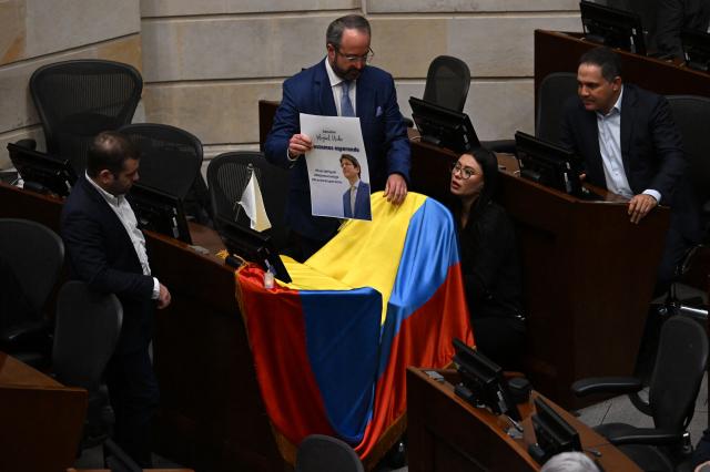 Lawmakers place a photo of Colombian senator and presidential candidate Miguel Uribe with the phrase "We are waiting for you" on a Colombian flag above his seat at the Congress in Bogota on June 9, 2025. Doctors treating a Colombian presidential hopeful shot twice in the head by a would-be assassin warned he was not responding well to treatment Monday and that his condition remained grave. Right-wing Senator Miguel Uribe, 39, was shot by a 15-year-old alleged hitman at close range while campaigning in Bogota on Saturday. (Photo by Raul ARBOLEDA / AFP)