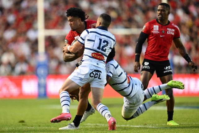 Toulon's New Zealand wing Leicester Fainga'anuku (L) is tackled by Castres' French centre Adrien Seguret (C) during the French Top14 playoff rugby union match between Rugby Club Toulonnais (Toulon) and Castres Olympique at the Stade Mayol in Toulon, south-eastern France, on June 14, 2025. (Photo by Christophe SIMON / AFP)
