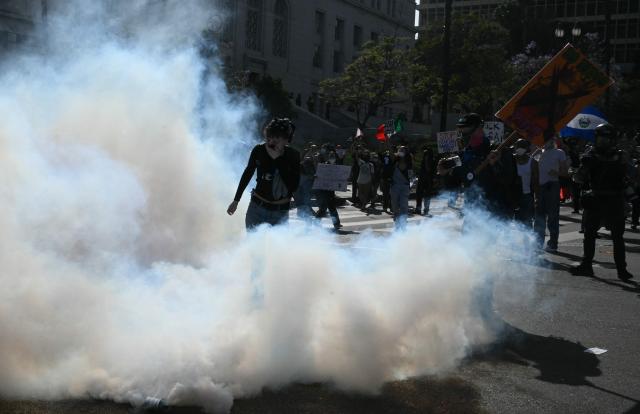 Protesters gathered to demonstrate against the Trump administration during the "No Kings" national rally walk though tear gas smoke as unlawful assembly was declared in Los Angeles on June 14, 2025, on the same day as President Trump's military parade in Washington, DC. Tens of thousands of protesters rallied nationwide Saturday against Donald Trump ahead of a huge military parade on the US president's 79th birthday -- as the killing of a Democratic lawmaker underscored the deep divisions in American politics. "No Kings" demonstrators took to the streets in New York, Los Angeles, Chicago, Philadelphia, Houston, Atlanta and hundreds of other cities across the United States to condemn what they call Trump's dictatorial overreach. (Photo by RONALDO SCHEMIDT / AFP)