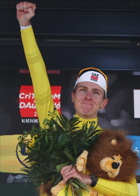 UAE Team Emirates XRG's Slovenian rider Tadej Poga?ar wearing the overall leader's yellow jersey celebrates winning the overall race on the podium of the 8th and final stage of the 77th edition of the Criterium du Dauphine cycling race, 133,3 km between Val-d'Arc and Val-Cenis - Plateau du Mont Cenis, on June 15, 2025. (Photo by Anne-Christine POUJOULAT / AFP)