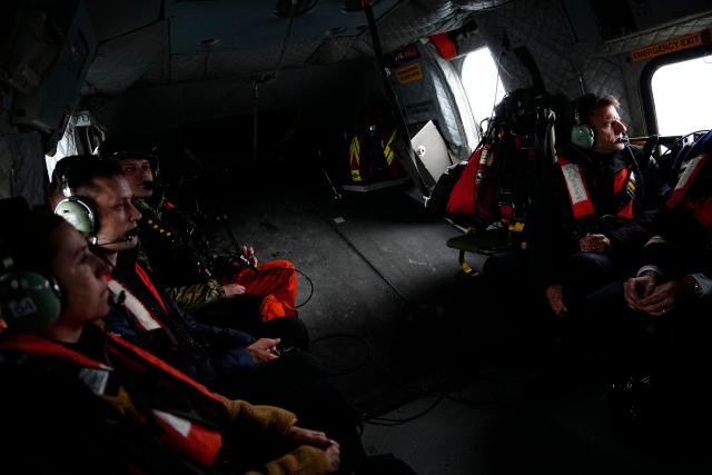 French President Emmanuel Macron (R),  Danish Prime Minister Mette Frederiksen (L) and Greenland's Prime Minister Jens-Frederik Nielsen sit inside a helicopter in Greenland, on June 15, 2025. French President Emmanuel Macron arrived on June 15 in Greenland, where he is expected to express "European solidarity and support" for the Danish autonomous territory coveted by US President Donald Trump, AFP journalists reported. Macron is the first foreign head of state to travel to the vast territory -- roughly nine times larger than the UK, with 80 percent of its area covered in ice -- since Trump's annexation threats. (Photo by Mads Claus Rasmussen / Ritzau Scanpix / AFP)