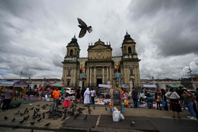 People stroll around in front of the Metropolitan Cathedral in Guatemala City on June 15, 2025. (Photo by JOHAN ORDONEZ / AFP)