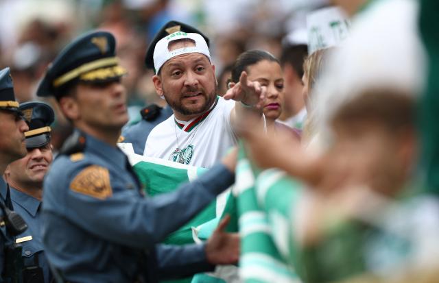 A fan of Palmeiras gestures next to police officers ahead of the Club World Cup 2025 Group A football match between Brazil's Palmeiras and Portugal's FC Porto at the MetLife stadium in East Rutherford, New Jersey on June 15, 2025. (Photo by FRANCK FIFE / AFP)