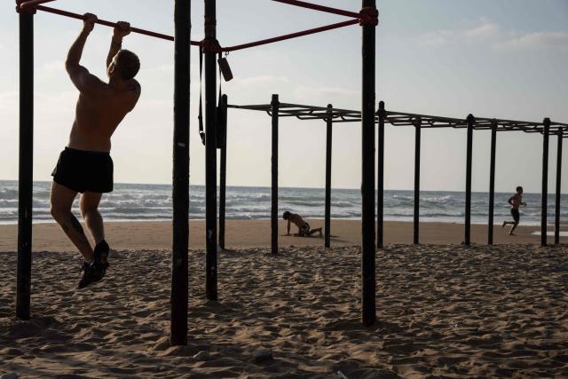 People exercise on the beach in Haifa, on June 16, 2025. Israel and Iran traded deadly fire for a fourth day on June 16 in their most intense confrontation in history, fuelling fears of a drawn-out conflict that could engulf the Middle East. (Photo by Maya Levin / AFP)