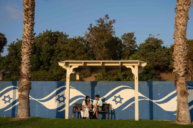 A couple sits by the beach in Haifa, on June 16, 2025. Israel and Iran traded deadly fire for a fourth day on June 16 in their most intense confrontation in history, fuelling fears of a drawn-out conflict that could engulf the Middle East. (Photo by Maya Levin / AFP)