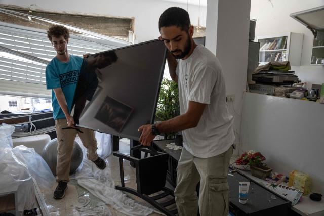 Volunteers help pack a television at an apartment in a building hit during an Iranian missile strike in Haifa, on June 17, 2025. Israel and Iran traded deadly fire for a fifth day on June 17 in their most intense confrontation in history, fuelling fears of a drawn-out conflict that could engulf the Middle East. (Photo by MAYA LEVIN / AFP)