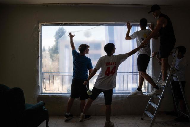 Volunteers help cover windows with plastic after they were bombed out in an Iranian missile strike in Haifa, on June 17, 2025. Israel and Iran traded deadly fire for a fifth day on June 17 in their most intense confrontation in history, fuelling fears of a drawn-out conflict that could engulf the Middle East. (Photo by MAYA LEVIN / AFP)