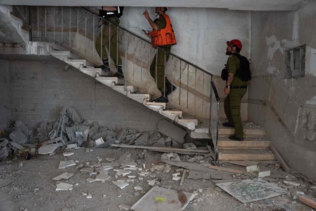 Israeli civil defence forces tour a building hit in an Iranian missile strike in Haifa, on June 17, 2025. Israel and Iran traded deadly fire for a fifth day on June 17 in their most intense confrontation in history, fuelling fears of a drawn-out conflict that could engulf the Middle East. (Photo by MAYA LEVIN / AFP)