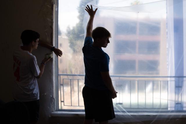 Volunteers help cover windows with plastic after they were bombed out in an Iranian missile strike in Haifa, on June 17, 2025. Israel and Iran traded deadly fire for a fifth day on June 17 in their most intense confrontation in history, fuelling fears of a drawn-out conflict that could engulf the Middle East. (Photo by MAYA LEVIN / AFP)