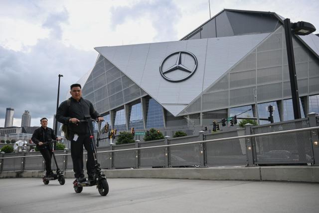 People drive electric scooters in front of the Mercedes-Benz stadium in Atlanta on June 18, 2025, on the eve of the Club World Cup 2025 Group A football match between US' Inter Miami and Portugal's FC Porto. (Photo by Federico PARRA / AFP)