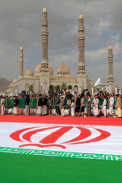 A giant Iranian flag is displayed on the ground as supporters of Yemen's Huthis gather for a rally in solidarity with Iran and Palestinians in the Gaza Strip while condemning Israel, outside the Saleh Grand Mosque in the Huthi-held capital Sanaa on June 20, 2025. (Photo by Mohammed HUWAIS / AFP)