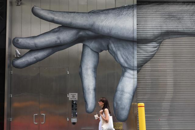 A woman walks past a mural in New York on June 23, 2025 after an excessive heat warning was issued for the New York City area. The United States is experiencing its first significant heat wave of the year, which began on June 20 across the Great Plains and expanding into parts of the Midwest and Great Lakes over the weekend, according to the National Weather Service (NWS). (Photo by TIMOTHY A. CLARY / AFP)