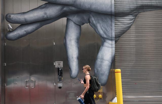 A woman walks past a mural in New York on June 23, 2025 after an excessive heat warning was issued for the New York City area. The United States is experiencing its first significant heat wave of the year, which began on June 20 across the Great Plains and expanding into parts of the Midwest and Great Lakes over the weekend, according to the National Weather Service (NWS). (Photo by TIMOTHY A. CLARY / AFP)