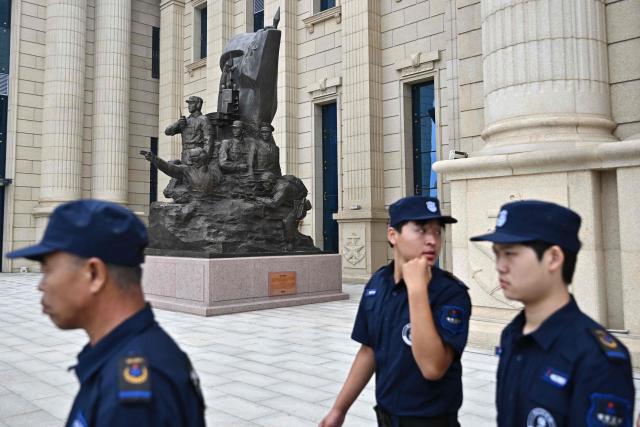 Security workers patrol during a media tour by the PLA Naval Museum, organized by the Chinese People's Liberation Army Navy (PLAN) ahead to Defence Ministers' Meeting of the Shanghai Cooperation Organization (SCO) Member States in Qingdao, in eastern China's Shandong province on June 25, 2025. (Photo by Pedro PARDO / AFP)