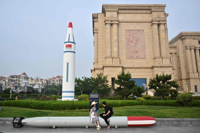 People sit on a torpedo during a media tour by the PLA Naval Museum, organized by the Chinese People's Liberation Army Navy (PLAN) ahead to Defence Ministers' Meeting of the Shanghai Cooperation Organization (SCO) Member States in Qingdao, in eastern China's Shandong province on June 25, 2025. (Photo by Pedro PARDO / AFP)