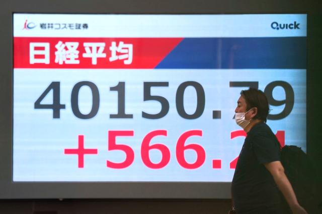 A man walks in front of an electronic quotation board displaying the Nikkei Stock Average closing price at 40,000 yen level on the Tokyo Stock Exchange in Tokyo on June 27, 2025. (Photo by Kazuhiro NOGI / AFP)