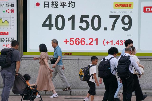 Pedestrians walk in front of an electronic quotation board displaying the Nikkei Stock Average closing price at 40,000 yen level on the Tokyo Stock Exchange in Tokyo on June 27, 2025. (Photo by Kazuhiro NOGI / AFP)