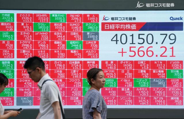 Pedestrians walk in front of an electronic quotation board displaying the Nikkei Stock Average closing price at 40,000 yen level on the Tokyo Stock Exchange in Tokyo on June 27, 2025. (Photo by Kazuhiro NOGI / AFP)