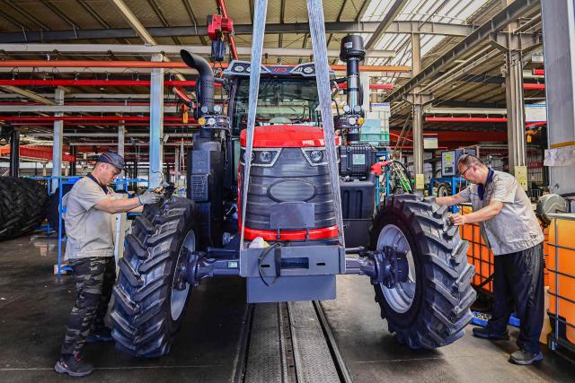 Employees work on a tractor assembly line at a factory in Qingzhou, in eastern China's Shandong province on June 27, 2025. (Photo by AFP) / China OUT