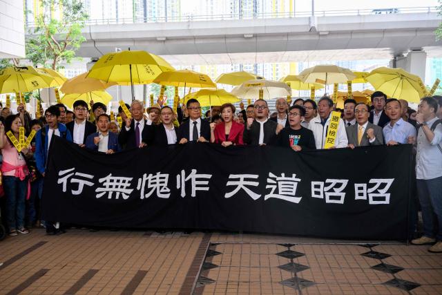 (FILES) (L-R behind banner) Pro-democracy activists Chung Yiu-wa, Cheung Say-yin, former Democratic Party lawmaker Lee Wing-tat, baptist minister Chu Yiu-ming, 74, law professor Benny Tai, 54, sociology professor Chan Kin-man, 59, lawmakers Tanya Chan and Shiu Ka-chun, and League of Social Democrats vice-chairman Raphael Wong, chant before entering the West Kowloon Magistrates Court in Hong Kong on November 19, 2018. Hong Kong's League of Social Democrats, one of the city's last remaining opposition parties after a five-year political crackdown by Beijing, said on June 27, 2025, that it will disband. (Photo by Anthony WALLACE / AFP)