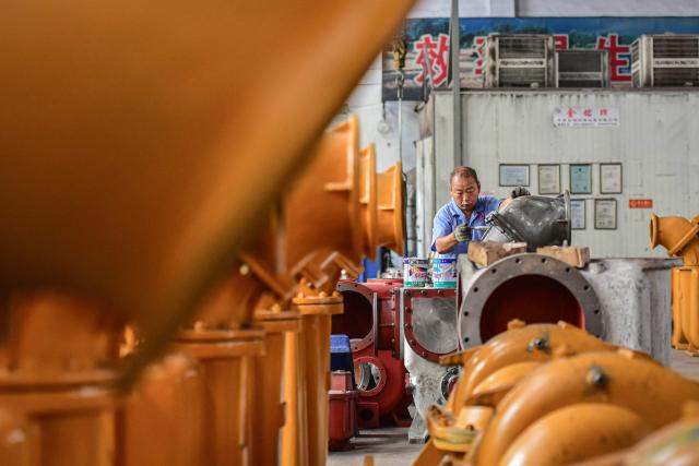 An employee works on a water pump production line at a factory in Qingzhou, in eastern China's Shandong province on June 30, 2025. (Photo by AFP) / China OUT