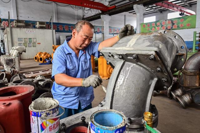 An employee works on a water pump production line at a factory in Qingzhou, in eastern China's Shandong province on June 30, 2025. (Photo by AFP) / China OUT