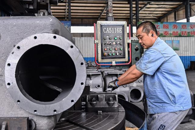 An employee works on a water pump production line at a factory in Qingzhou, in eastern China's Shandong province on June 30, 2025. (Photo by AFP) / China OUT