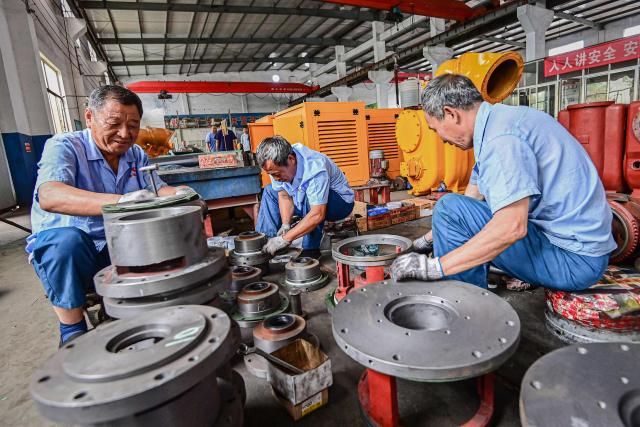 Employees work on a water pump production line at a factory in Qingzhou, in eastern China's Shandong province on June 30, 2025. (Photo by AFP) / China OUT