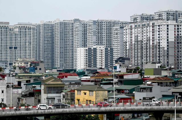 Vehicles drive on a bridge in front of low-rise and high-rise buildings in Hanoi on June 30, 2025. (Photo by Nhac NGUYEN / AFP)