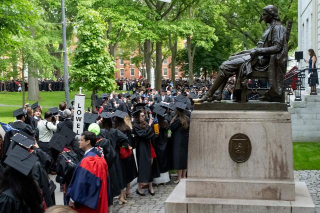(FILES) Graduating students stand next to a statue of John Harvard at the 374th Harvard Commencement in Harvard Yard in Cambridge, Massachusetts, on May 29, 2025. The Trump administration on June 30, 2025, accused Harvard of violating the civil rights of its Jewish and Israeli students and threatened to cut off all federal funding if the university does not take urgent action. Harvard has been at the forefront of Donald Trump's campaign against top universities after it defied his calls to submit to oversight of its curriculum, staffing, student recruitment and "viewpoint diversity." (Photo by Rick Friedman / AFP)