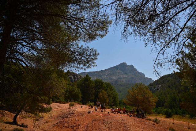 Adults and children search for dinosaur eggs at the Mount Sainte-Victoire site, near Aix-en-Provence in southern France, on June 25, 2025. Armed with a hand brush, a paleontologist meticulously inspects a mound of red clay at the foot of Mount Sainte-Victoire, in search of very specific fossils dating back some 75 million years: dinosaur eggs. (Photo by Christophe SIMON / AFP)