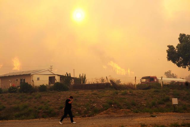 Smoke and flames rise from a forested area following a wildfire in the Seferihisar district of Izmir, Turkey, on June 30, 2025. Rescuers have evacuated more than 50,000 people, mostly from Turkey's western Izmir province, as firefighters battled a string of wildfires, the AFAD disaster agency said Monday. (Photo by Ahmet Ayberk Cimen / AFP)