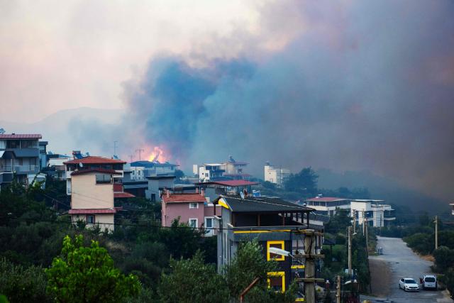 Smoke and flames rise from a forested area following a wildfire in the Seferihisar district of Izmir, Turkey, on June 30, 2025. Rescuers have evacuated more than 50,000 people, mostly from Turkey's western Izmir province, as firefighters battled a string of wildfires, the AFAD disaster agency said Monday. (Photo by Ahmet Ayberk Cimen / AFP)