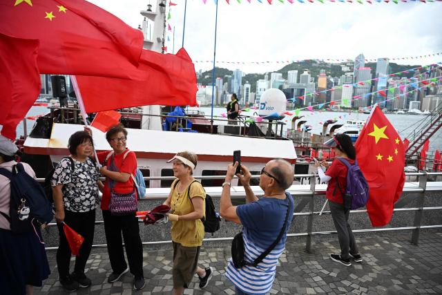 Pro-Beijing supporters wave China flags on the edge of Hong Kong's Victoria Harbour to mark the 28th anniversary of Hong Kong's handover from Britain to China in Hong Kong on July 1, 2025. (Photo by Peter PARKS / AFP)