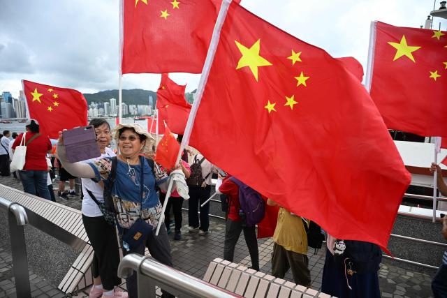 Pro-Beijing supporters wave China flags on the edge of Hong Kong's Victoria Harbour to mark the 28th anniversary of Hong Kong's handover from Britain to China in Hong Kong on July 1, 2025. (Photo by Peter PARKS / AFP)