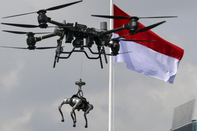 A robotic police dog is deployed to a location by a drone as part of a crime-handling skill demonstration during the 79th anniversary celebration of the Indonesian National Police held at the National Monument (known as Monas) in Jakarta on July 1, 2025. (Photo by BAY ISMOYO / AFP)