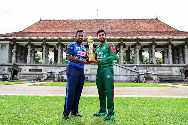 Sri Lanka's captain Charith Asalanka (L) poses with the trophy alongside his Bangladesh counterpart Mehidy Hasan Miraz on the eve of their first one-day international (ODI) cricket match in Colombo on July 1, 2025. (Photo by Ishara S. KODIKARA / AFP)