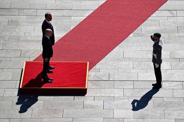 German Chancellor Friedrich Merz (L, background) and Luxembourg's Prime Minister Luc Frieden take the salute before listening to their national anthems and reviewing a military honor guard during an official welcome ceremony in front of the Chancellery in Berlin on July 1, 2025. (Photo by John MACDOUGALL / AFP)