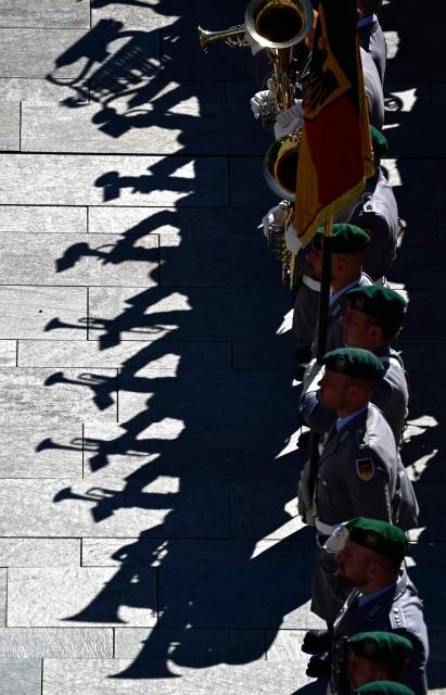 Brass musicians of an honor guard cast their shadows on the ground in front of the Chancellery during an official welcome ceremony with the German Chancellor and Luxembourg's Prime Minister in Berlin on July 1, 2025. (Photo by John MACDOUGALL / AFP)