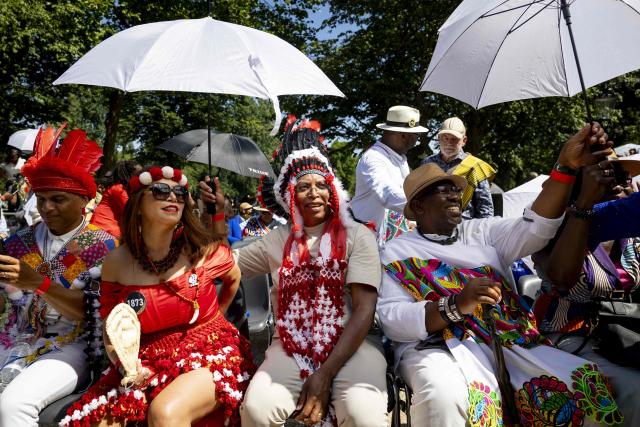 People wait before taking part in the 23rd National Slavery Commemoration day at the National Slavery Monument in Amsterdam's Oosterpark on July 1, 2025. The ceremony commemorates the abolition of slavery on July 1, 1863 in Netherland's former colony Suriname and the Caribbean part of the Dutch Kingdom. (Photo by Ramon van Flymen / ANP / AFP) / Netherlands OUT