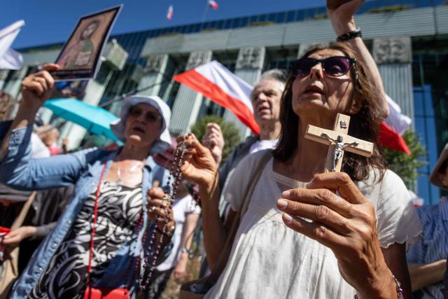 Supporter of Karol Nawrocki, president elect supported by Poland's right-wing Law and Justice (PiS) party, holds crucifix as she and other participants wait in front of the Supreme Court building in Warsaw on July 1, 2025 for the announcement of the ruling on the validity of the presidential election. (Photo by Wojtek RADWANSKI / AFP)